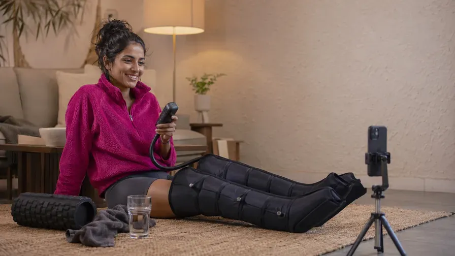An athlete in recovery boots at home, phone in hand