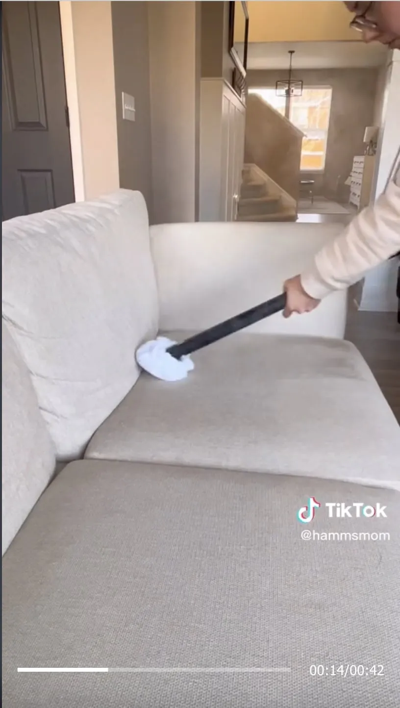A creator uses a Dupray cleaning attachment on a sofa.