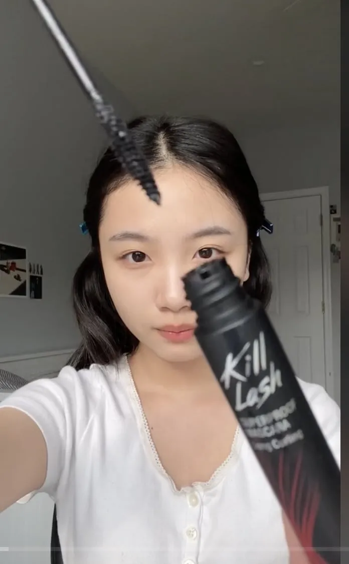 A creator holds the CLIO Kill Lash mascara tube and wand close to the camera.