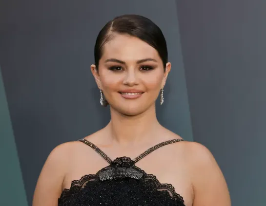 Selena Gomez with slicked-back hair in a black lace gown at a red carpet event