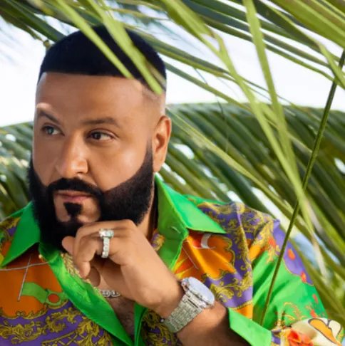 DJ Khaled in a bright patterned silk shirt and diamond watch among palm fronds
