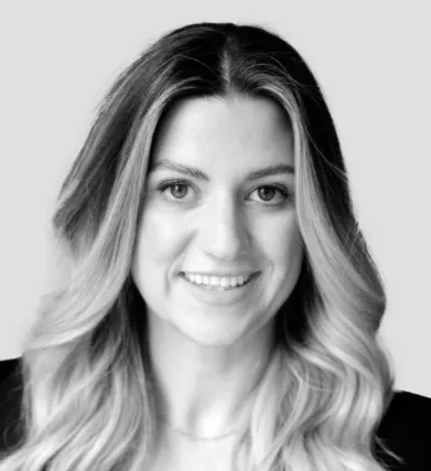 Black-and-white headshot of a smiling woman with long wavy blonde hair