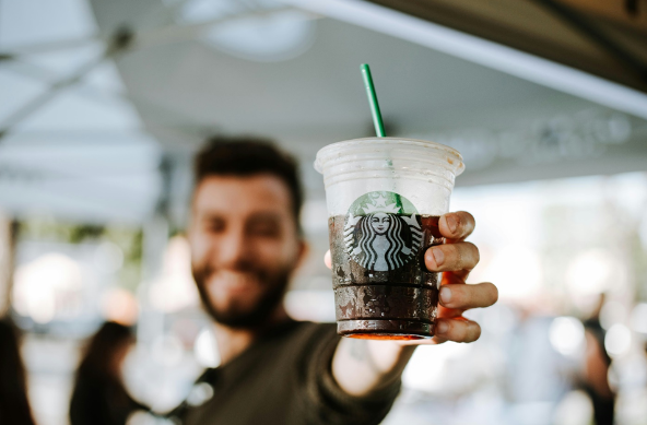 A man smiling and holding a Starbucks drink.