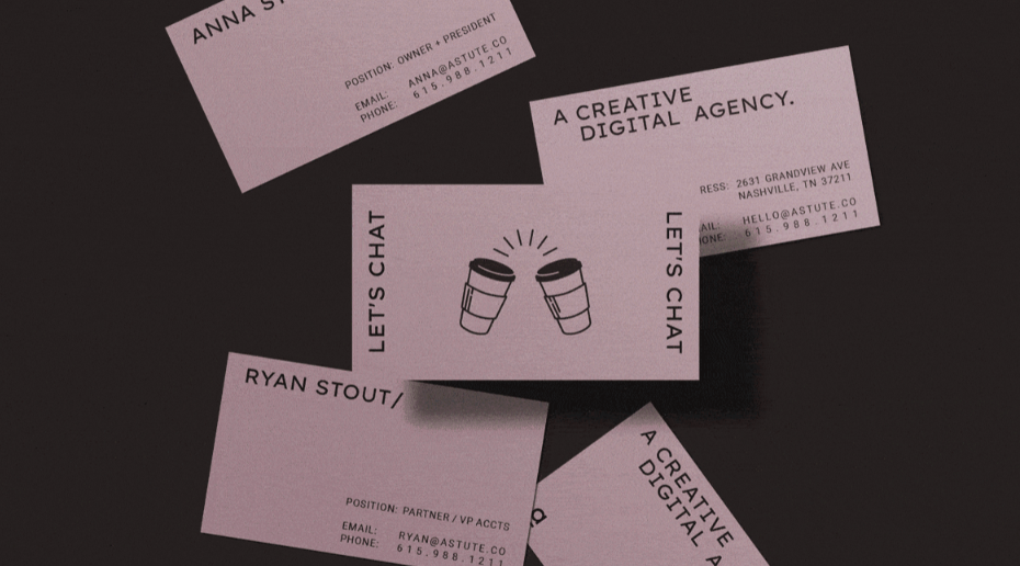 Several light-purple business cards for Astute Communications are scattered across a dark, textured surface, showcasing a "Creative Digital Agency" based in Nashville. The central card features an illustration of two coffee cups clinking together under the text "LET'S CHAT," while surrounding cards display contact information for team members like Anna and Ryan Stout. Each card maintains a minimalist aesthetic with clean, sans-serif typography that emphasizes the agency's modern approach to digital branding.